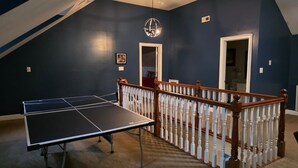 A room with a ping pong table, a chandelier, and a wooden railing. - Large Private Home Near Charlotte Sleeps 15  Workspaces and Land - NO PETS (Dallas)
