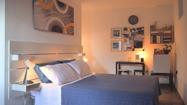 A bedroom with a bed, bedside table, lamp, wall clock, and a bulletin board with photos and notes. - B & B Family in the heart of the Village of Aieta (Cs) (Aieta)