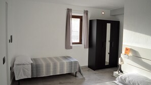 A bedroom with two beds, a wardrobe, a window with curtains, and a bedside table with a lamp. - B & B Family in the heart of the Village of Aieta (Cs) (Aieta)