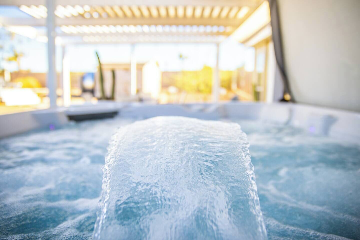 Ein Whirlpool mit freiem Blick auf die Wasseroberfläche und einem unscharfen Hintergrund, der eine Gartenpergola andeutet.