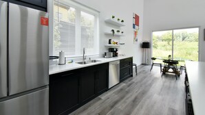 Une cuisine moderne avec des meubles noirs, des appareils en acier inoxydable et un coin repas doté d’une table et de chaises en verre.