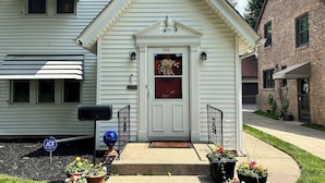 A white house with a front door, a mailbox, and a small porch with potted plants. - The Portage Place: 3BR 2 mi from ND w/ king suite (South Bend)