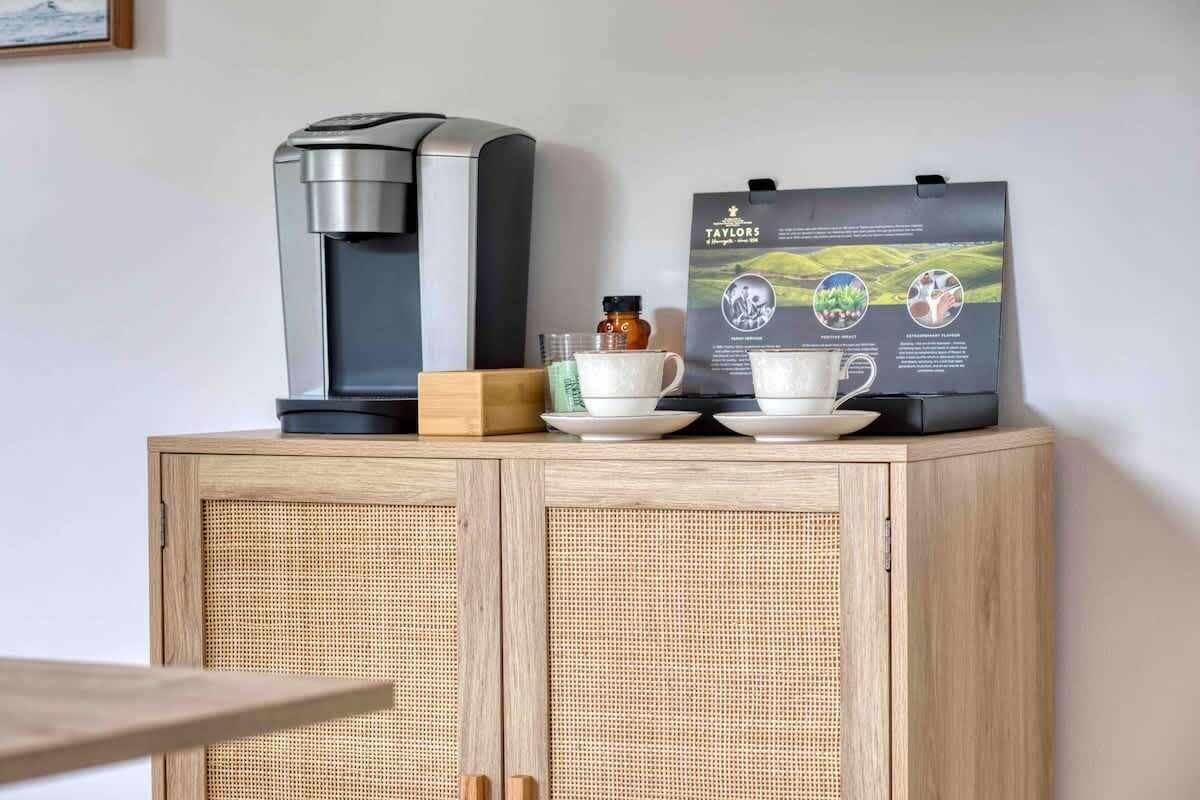 Une machine à café, une boîte et un sac de café sur un meuble en bois.