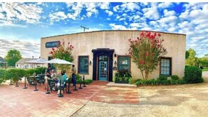 A building with a sign reading "WELLINGTON" and a brick patio area with tables and chairs.