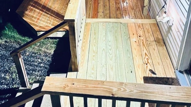 A wooden deck with Adirondack chairs, a small table, and string lights.