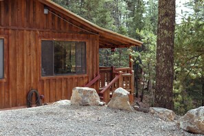 Une cabane en bois dotée d’un porche, de grandes fenêtres et d’une allée gravillonnée.