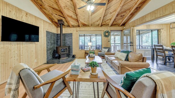 Ein Wohnzimmer mit Holzvertäfelung, einem Kamin, einem Deckenventilator und einem großen Fenster.