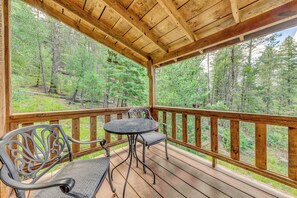 Une terrasse en bois avec une table et des chaises, donnant sur une zone boisée.