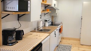 Eine kompakte Küche mit Mikrowelle, Kaffeemaschine und Geschirrspüler.