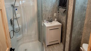 Ein modernes Badezimmer mit einer gläsernen Dusche, einem Waschbecken mit Waschtisch und einer Toilette.