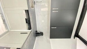 Een badkamer met een douche, toilet en wastafel.