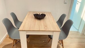 Een eettafel met een licht houten afwerking, omringd door vier grijze stoelen met houten poten.