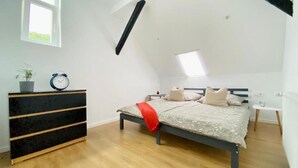 Een slaapkamer met een bed, een dressoir, een klok en een raam.