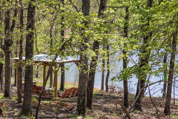 A gazebo with benches overlooking a lake, surrounded by trees.