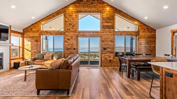 Un loft espacioso con techo alto, paredes de madera, ventanas amplias, un rincón de descanso acogedor y un comedor.