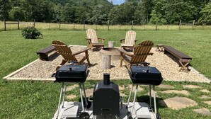 Un espace extérieur aménagé avec des chaises Adirondack et un barbecue.