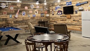 Une pièce équipée d’une table de billard, de chaises, d’une table ronde et d’un mur décoré de logos de marques de bière.