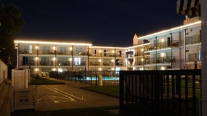 Ein mehrstöckiges Hotel mit beleuchteten Balkonen und einem Schwimmbad.