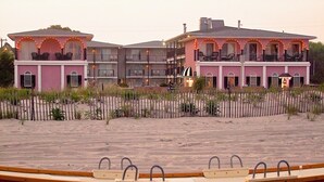 Ein Strandhotel mit mehreren Balkonen und einem Sandstrand davor.