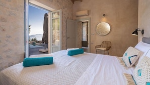 Un dormitorio con una cama grande, una silla, un espejo redondo y vistas al exterior.