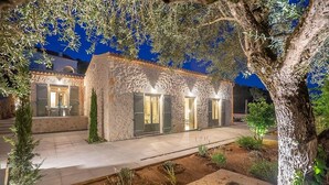 Un edificio de piedra con entrada de tejas y un sendero bien iluminado.