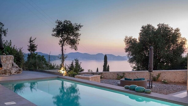 Una piscina con vistas al mar y a las montañas al anochecer.