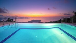 An empty swimming pool with a view of the sunset over the sea and a distant island. - Impressive Stone Villa, A/C, Private Pool, Sweeping Sea Views to Assos Bay & Magnificent Sunsets! (Defaranata)