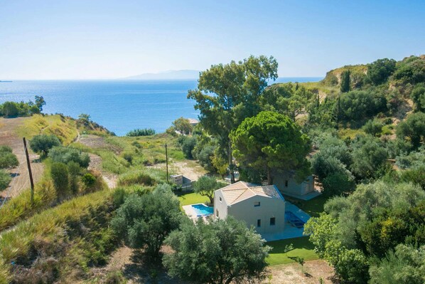 A coastal property with a house surrounded by lush greenery and a view of the sea.