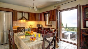 Une cuisine avec des meubles en bois, un réfrigérateur en acier inoxydable et une table à manger dressée avec des fruits et des verres.