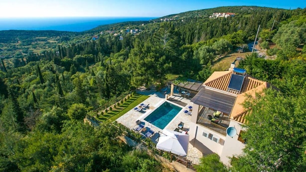 Une villa dotée d’une piscine, de panneaux solaires et offrant une vue panoramique sur la mer et les collines.