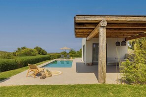 A modern house with a pool, outdoor seating, and a view of the landscape.