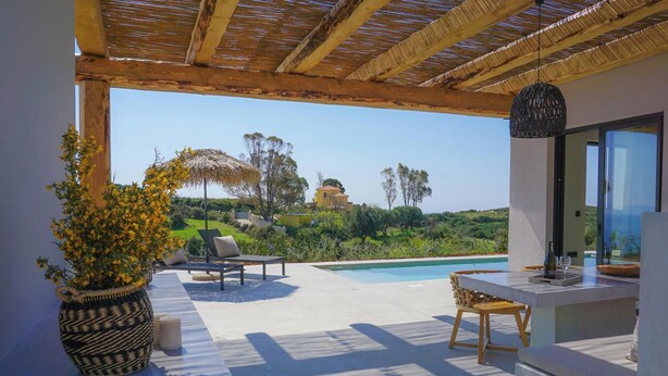 Eine moderne Außenpatio mit Pool, Liegestühlen und Blick auf eine Hügelkette.