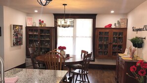 A kitchen with granite countertops, wooden cabinets, a dining area with a table and chairs, and a decorative globe light fixture.