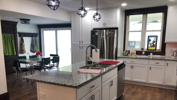A modern kitchen with white cabinets, a stainless steel refrigerator, and a granite countertop.
