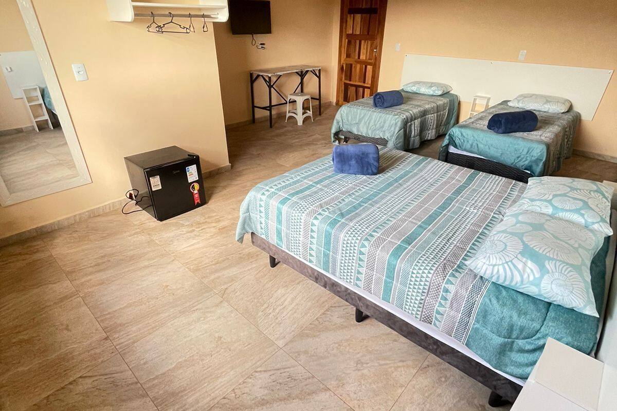 A bedroom with two beds, a small table, a chair, a wardrobe, and a mirror.
