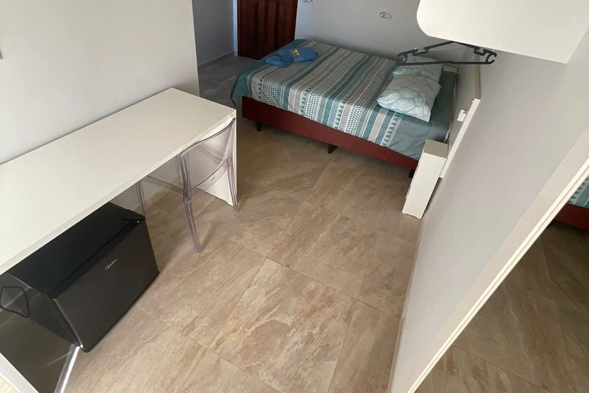 A compact bedroom with a bed, a desk, and a wardrobe.