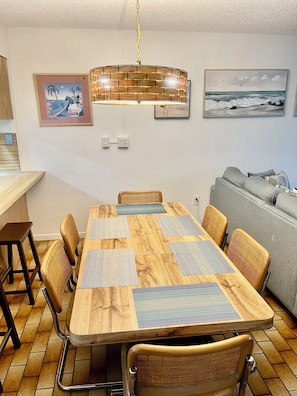 A dining area with a wooden table, woven chairs, and a hanging light fixture.