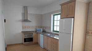 A compact kitchen with a stove, oven, microwave, sink, and a refrigerator. - Villa Martina, Lugar Ideal Para Disfrutar Sol@ o en Familia (Playa Blanca)