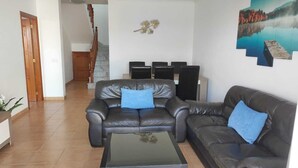 A living room with two leather sofas, a glass coffee table, and a painting of a lake on the wall. - Villa Martina, Lugar Ideal Para Disfrutar Sol@ o en Familia (Playa Blanca)