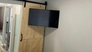 Ein Schlafzimmer mit einem Bett, einem Holzschrank, einer Schiebetür und einem an der Wand befestigten Fernseher.