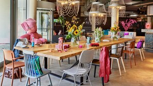 A spacious dining area with a long wooden table, modern chairs, and decorative lighting. - Moxy Karlsruhe (Karlsruhe)