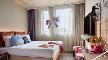 A hotel room with a bed, a desk, a TV, and a window with curtains.