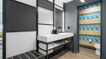 Un baño moderno con un lavamanos blanco, estanterías negras y un inodoro.