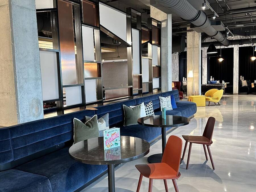 Un espace de détente moderne avec un canapé bleu, des tables rondes et des chaises orange.
