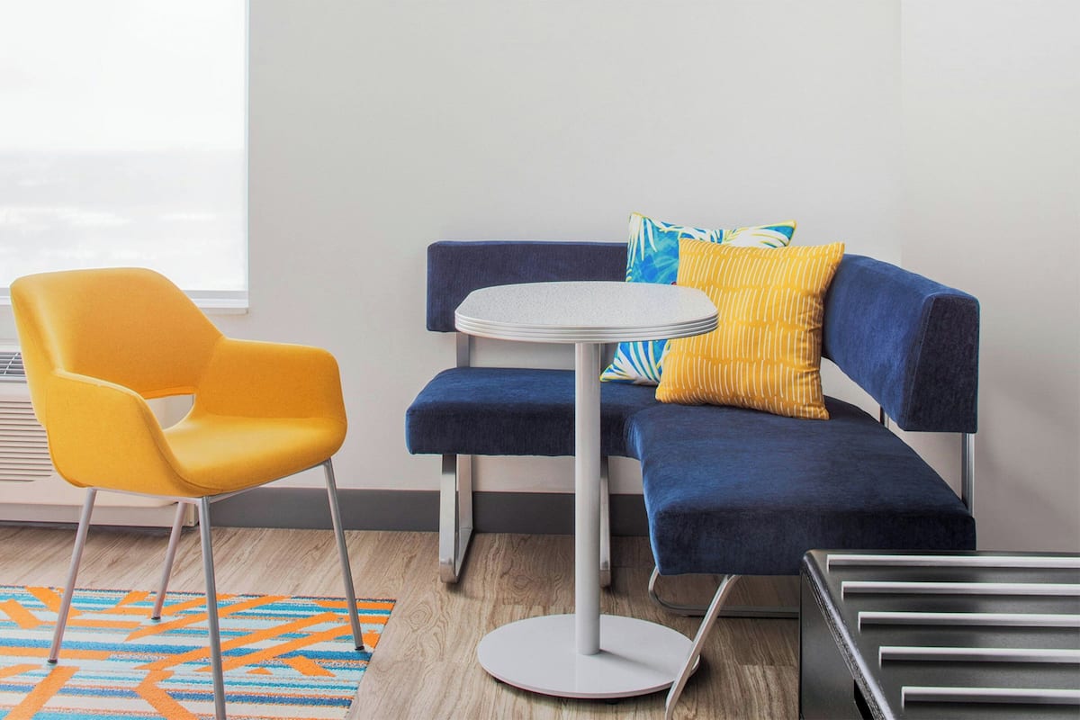 Ein modernes Zimmer mit einem blauen Sofa, einem gelben Sessel und einem kleinen runden Tisch.