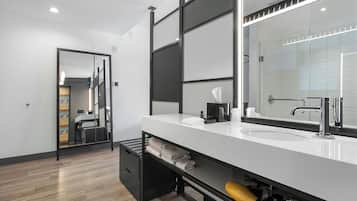 A modern bathroom with a large mirror, white sink, and black storage.