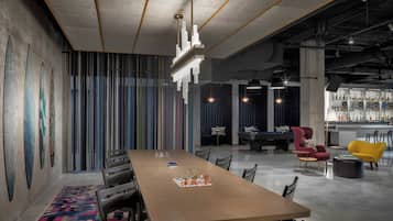 Une salle de réunion moderne, dotée d’une longue table, de chaises et d’un coin bar avec des tabourets.