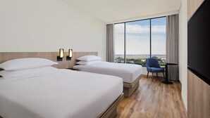 A hotel room with two beds, a large window with a city view, a desk with a chair, and a flat-screen TV. - Fairfield By Marriott Jakarta Soekarno-Hatta Airport (Jakarta)