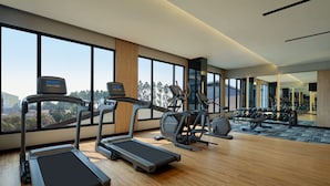 A modern gym with treadmills, elliptical machines, and weight equipment. Large windows offer a view of the city. - Fairfield By Marriott Jakarta Soekarno-Hatta Airport (Jakarta)
