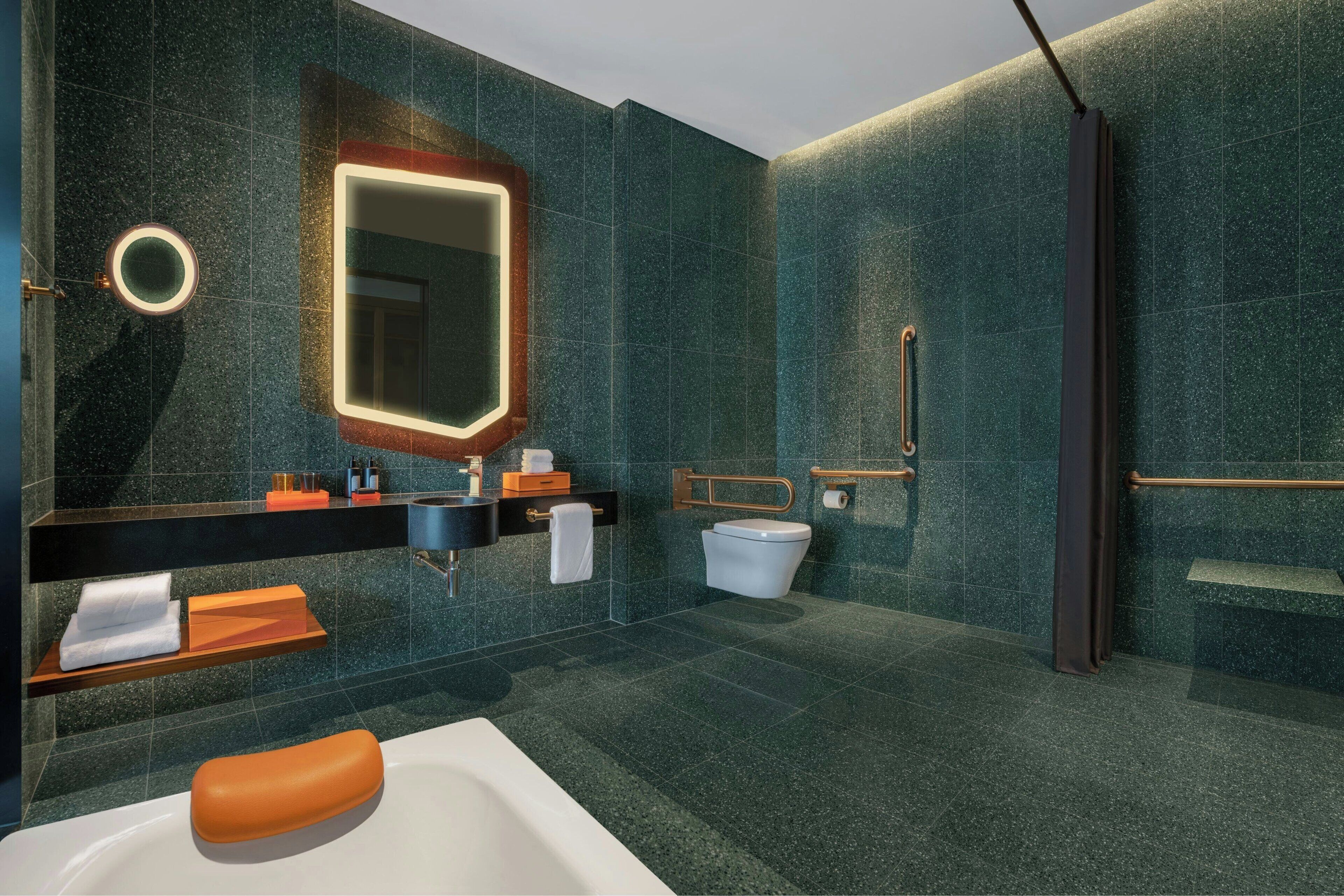 A modern bathroom with a large mirror, a bathtub, a toilet, and a shower area.